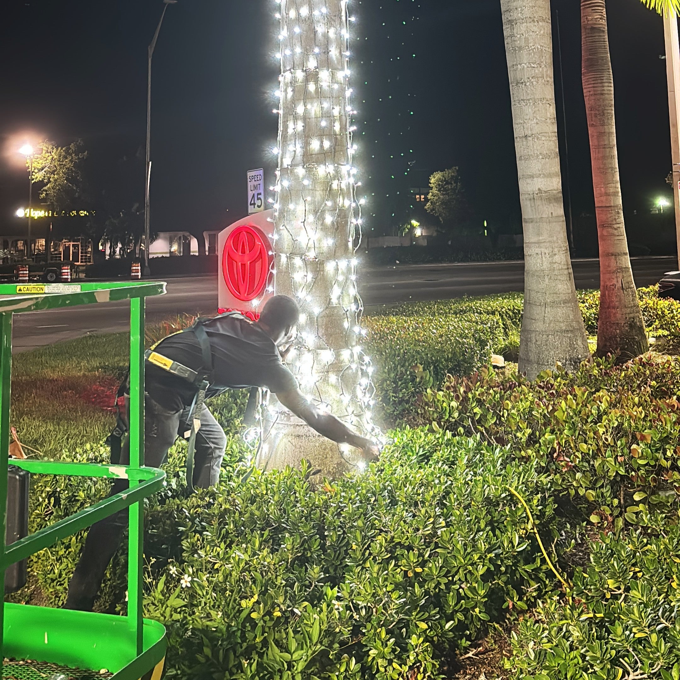 Fantasy Lab Studio Employee on a lift working on outdoor lighting installation at night.