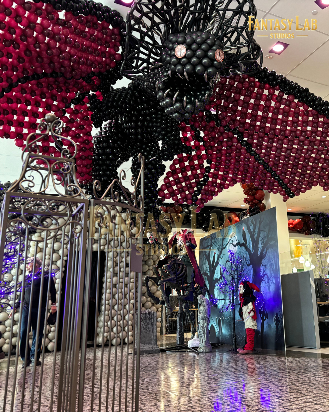 Giant balloon bat suspended over a gothic set with gate and scenic elements.